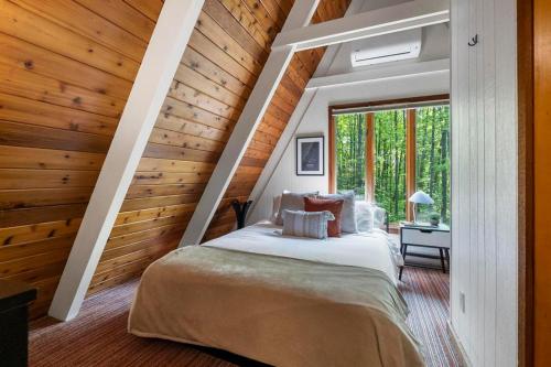 Un dormitorio con una cama en una habitación con paredes de madera. en Hansel Htte Cozy A-frame At Schuss Mountain, en Bellaire
