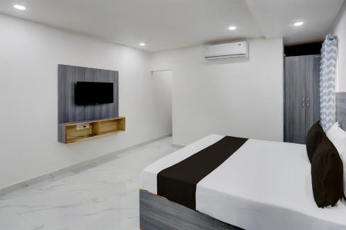 a bedroom with a bed and a tv on a wall at HOTEL O MURARI in Karīmnagar