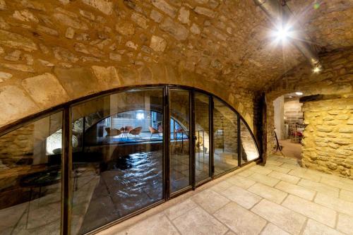 a room with a large glass window in a stone wall at La Prévôté - Hôtel Particulier & Restaurant in LʼIsle-sur-la-Sorgue