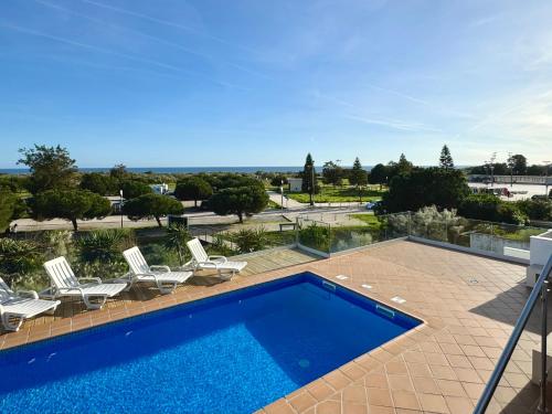 a swimming pool with chairs and a patio with a view at Pérola do Oceano in Manta Rota