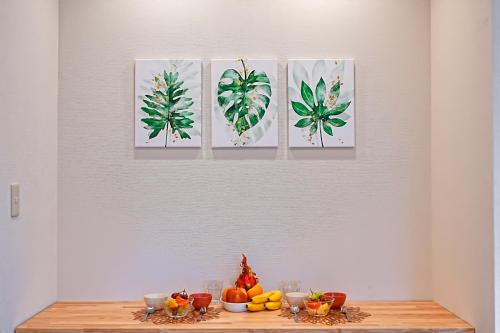 four paintings on a wall above a table with fruit at Unite Stay Gyotoku in Tokyo