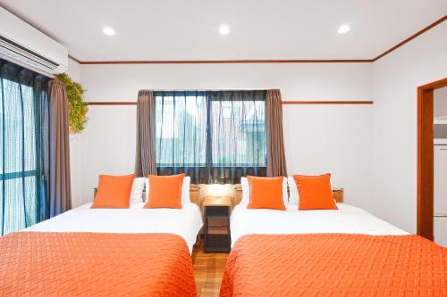 two beds in a room with orange pillows at Unite Stay Gyotoku in Tokyo
