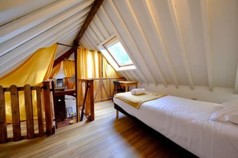 Gîte de l'Ecrin de l'Andelle - Un écrin de nature entre rivière et forêt في Morville-sur-Andelle: غرفة نوم بسرير ونافذة في العلية