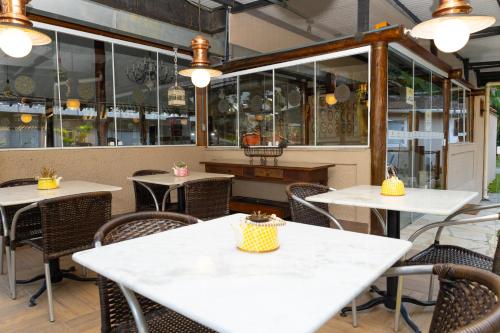 a restaurant with white tables and chairs and windows at Pousada Reserva Penedo in Penedo