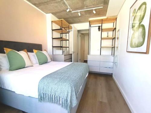 a bedroom with a bed in a room with shelves at Kkape Sands - Peak Views From Sea Point Pad in Cape Town