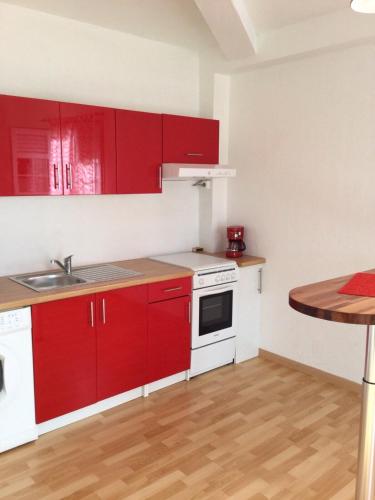 a small kitchen with red cabinets and a wooden floor at Bright F2 Apartment in Saint-Claude