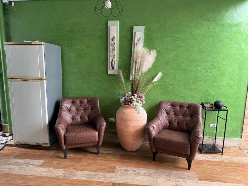a green wall with two chairs and a vase with flowers at Espaço Varanda in Sao Paulo