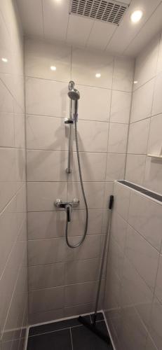 a shower with a hose in a white tiled bathroom at Haus Im Wald 