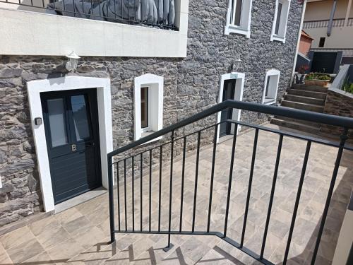 una casa con una porta nera e un balcone di Adelaide's Cottage a Ponta do Pargo