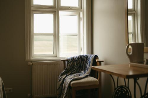 a room with a chair and a table and a window at Guesthouse Storu-Laugar in Laugar