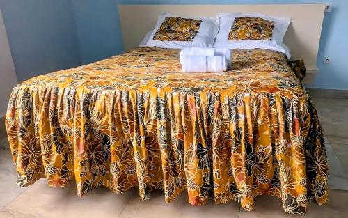 a bed with a orange and black comforter and pillows at Villa le chant des Alizés 