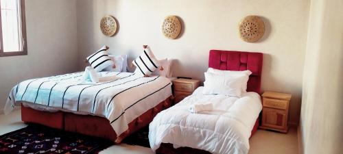 a bedroom with two beds and a chair at Hôtel Restaurant Dar Al Madina in Tinerhir