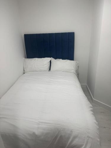 a white bed with a blue headboard in a room at Cozy Lodge in Rochester