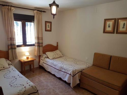 a room with two beds and a couch and a window at La Vista de Gredos in Navarredonda de Gredos