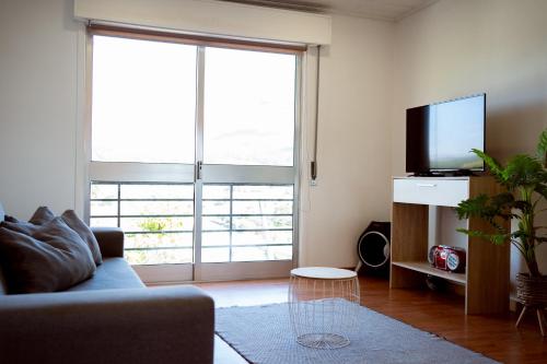 a living room with a couch and a large window at Casa da Estação, vista rio Tâmega e Senhora da Graça in Veade