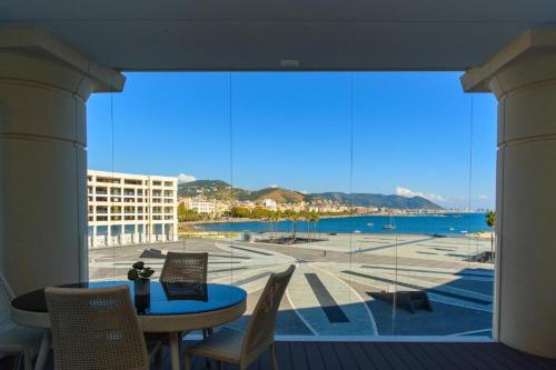 a patio with a table and chairs and a large window at Crescent Luxury Retreat - Seafront Apartments in Salerno