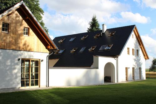 a house with a black roof and a green lawn at Penzion Fořtovna in Častrov
