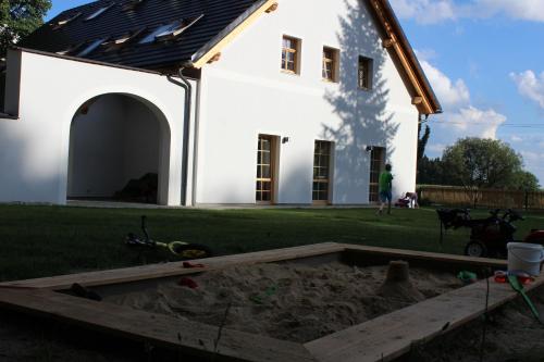 a sandbox in front of a white house at Penzion Fořtovna in Častrov