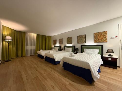 a hotel room with three beds with green curtains at City Homestay in Miri