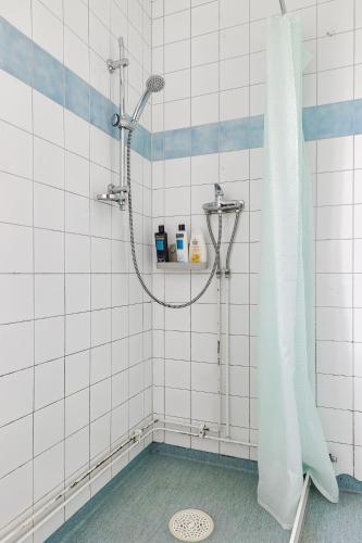 a shower in a white tiled bathroom with a shower curtain at Bright & Spacious Getaway in Lötgärde