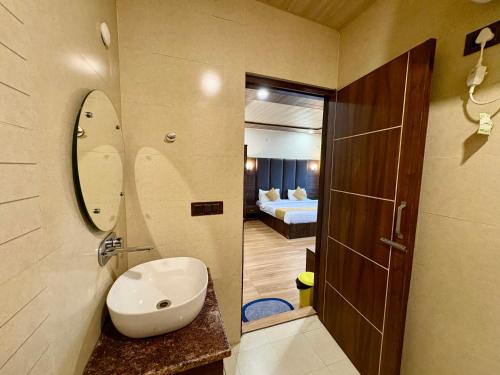 Un baño con lavabo y espejo y un dormitorio. en Hotel Jannat, en Dalhousie