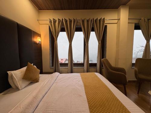 Un dormitorio con una cama con una ventana grande. en Hotel Jannat, en Dalhousie