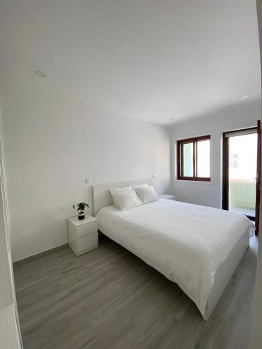 a white bedroom with a large bed and a window at T4 Furadouro with sea view in Furadouro
