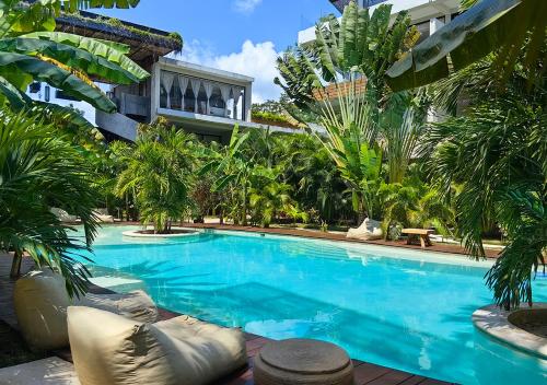 une piscine devant un immeuble avec des palmiers dans l'établissement Boho Chic Loft- Stunning Terrace in Central Tulum, à Tulum