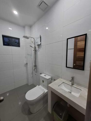 a white bathroom with a toilet and a sink at Carolina Siargao Homestay in General Luna