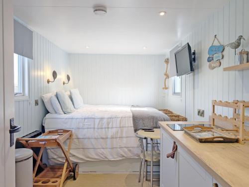 a small bedroom with a bed and a kitchen at The Shepherd's Hut on the Beach - Pagham - Sea Front in Pagham