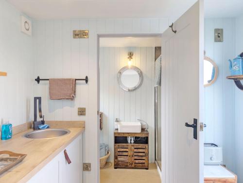 a small bathroom with a sink and a mirror at The Shepherd's Hut on the Beach - Pagham - Sea Front in Pagham
