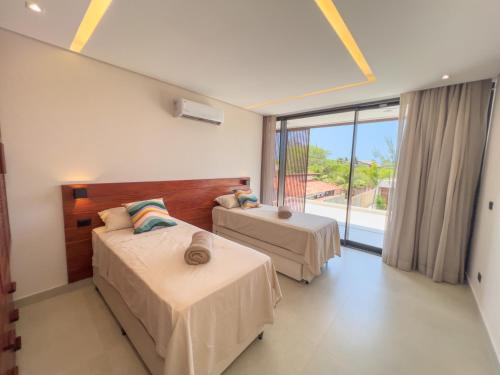 une chambre avec deux lits et une grande fenêtre dans l'établissement Vila Libelula, à São Miguel do Gostoso