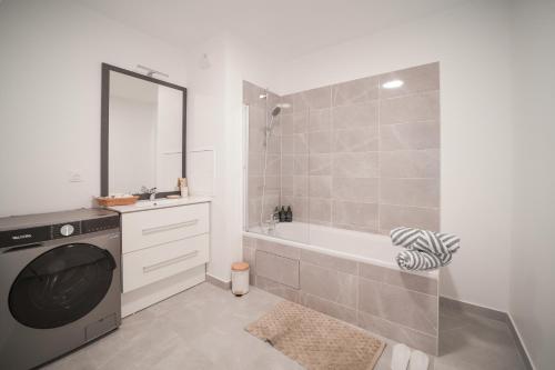 ein Badezimmer mit einer Badewanne und einer Waschmaschine in der Unterkunft Appartement F3 Neuf Vue sur la Seine avec Parking Gratuit Proche Paris Tour Eiffel & Disney in Cormeilles-en-Parisis