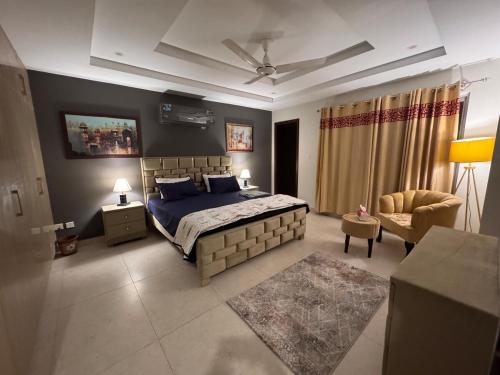 a bedroom with a king sized bed and a chair at JW Apartments in Dargai
