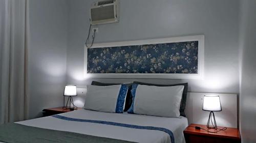 a bedroom with a bed with two lamps and a painting at Hotel Pousada Oasis Park in Jaboticabal