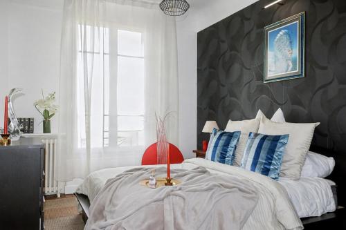 a bedroom with a large bed with blue and white pillows at Urban Lux Colombes in Colombes