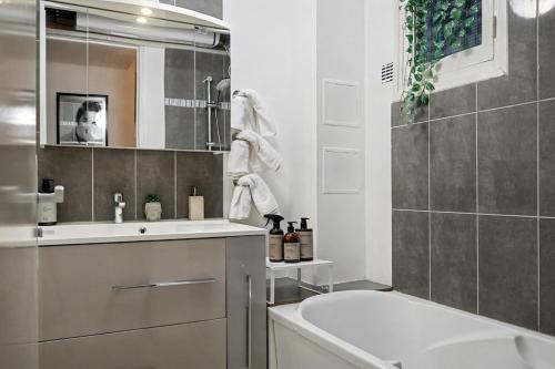 a bathroom with a tub and a sink and a mirror at Urban Lux Colombes in Colombes