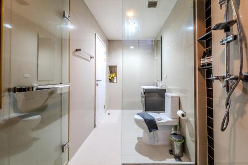 a bathroom with a toilet and a glass shower at Elegant 1BR Garden-View Condo - The Deck Patong in Patong Beach