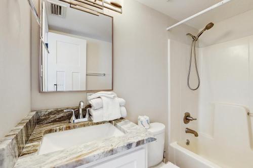 ein weißes Badezimmer mit Waschbecken und Spiegel in der Unterkunft Baydream Believer in Fort Morgan