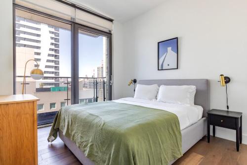 ein Schlafzimmer mit einem Bett und einem großen Fenster in der Unterkunft Blueground Long Island City rooftop nr Gantry Park NYC-1767 in Long Island City