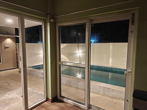 two sliding glass doors in a room with a swimming pool at Maple Dreams Retreat- A Pool side Villa in Pondicherry