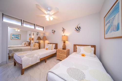 a bedroom with two beds and a ceiling fan at Kulakane 306 · KK 306 Remodeled BeachFront 2BD w Ocean Views AC in Kahana