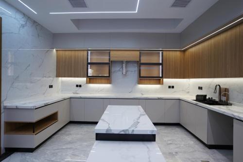 a large kitchen with white counters and wooden cabinets at Villa, 6BR with swimming pool next to Stars avenue in Jeddah