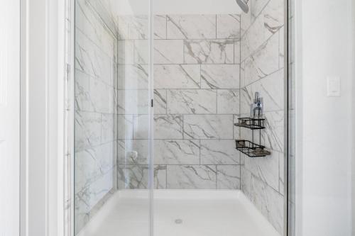a shower with white marble walls and a glass door at Blueground Del Valle pool nr McKinney Falls ATX-352 in Austin