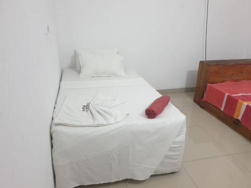 a bed with white sheets and a red pillow on it at Eulália villa in Vila Praia Do Bilene