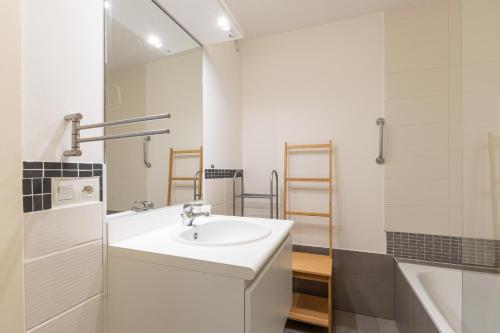 a white bathroom with a sink and a bath tub at Plaza in Sint-Idesbald
