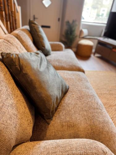 a brown couch with two pillows on it at La Casa De Campo in Long Preston