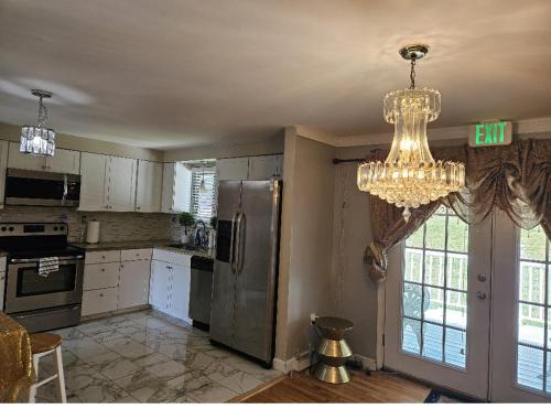Il comprend une cuisine avec un réfrigérateur en acier inoxydable et un lustre. dans l'établissement Welcome and dreamthome, à Monroeville
