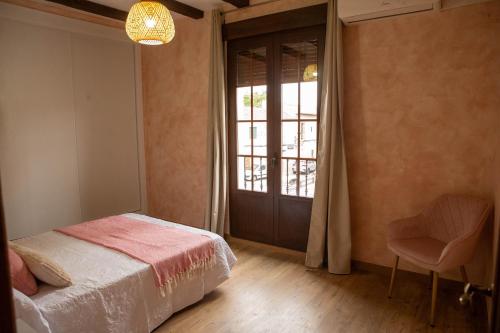 a bedroom with a bed and a window and a chair at Los Soportales-Casa historica siglo XVI a 20 minutos de Puy du Fou in Orgaz