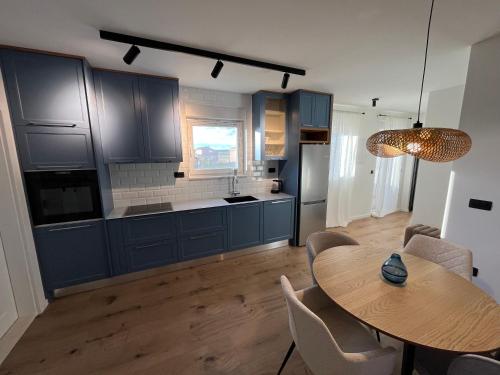 a kitchen with blue cabinets and a wooden table at Marta Apartment in Čitluk